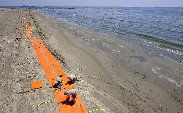 Members of the U.S. National Guard install floating dams to protect a beach from the Mexico Gulf oil spill on Grand Isle, south Louisiana, the United States, May 27, 2010. [Zhang Jun/Xinhua]