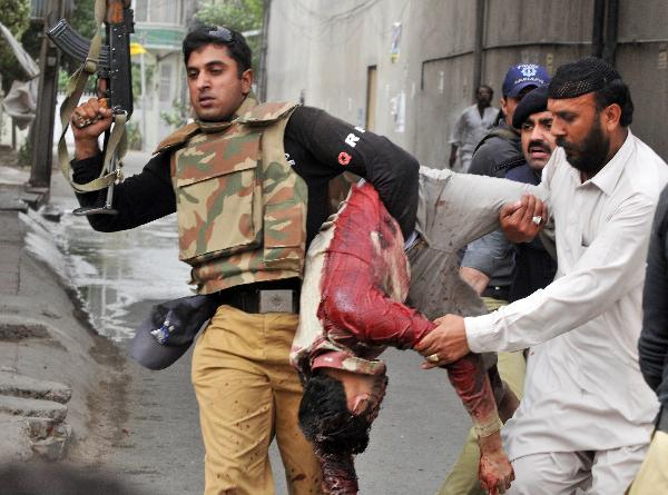 Pakistani police take a victim outside a mosque in Lahore. Gunmen wearing suicide vests have stormed two Pakistani mosques belonging to a minority sect in Lahore, bringing carnage to Friday prayers and killing at least 80 people, officials said. [Xinhua/AFP]