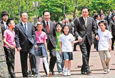Premier Wen Jiabao, Republic of Korea President Lee Myung-bak (center) and Japanese Prime Minister Yukio Hatoyama (right) walk with elementary school students on Sunday as they arrive to plant a tree in Seogwipo, on the ROK’s Jeju Island.[Ahn Young-Joon/Reuters]