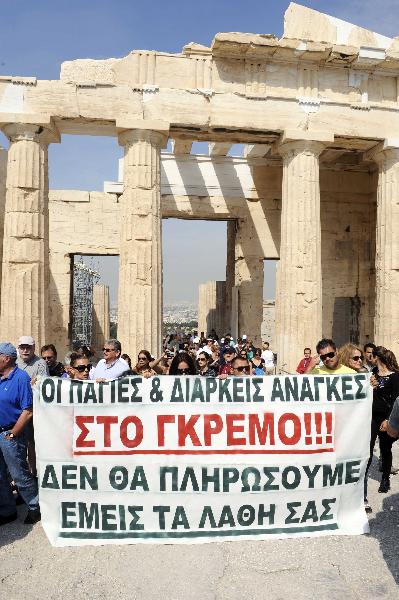 Greek protestors hold a banner with 'Our needs are thrown down the cliff. We will not pay for their mistakes' during an inspection by Greek President Karolos Papoulias on the Acropolis Hill in Athens, Greece, on May 25, 2010. The short-term contract employees demanded back pay and more job positions. (Xinhua/Phasma)