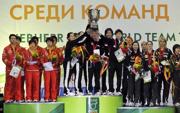 Singaporean table tennis team memebers(C) hold the trophy during the awarding ceremony at the 50th World Team Table Tennis Championships in Moscow, capital of Russia, on May 30, 2010. (Xinhua/Tao Xiyi)