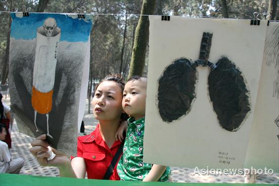 A mother and her son on Sunday look at artwork promoting tobacco bans painted by volunteers from Liaocheng city of Shandong province. [Asianewsphoto]