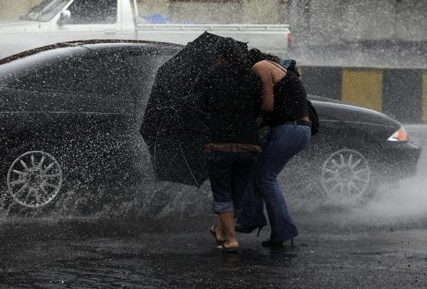 Pedestrians try to avoid being splashed by a passing car in the rain caused by Tropical Storm Agatha in Guatemala City May 29, 2010. Guatemala declared a state of emergency on Saturday as heavy rain from Tropical Storm Agatha lashed the Central American nation.[Xinhua/Reuters]