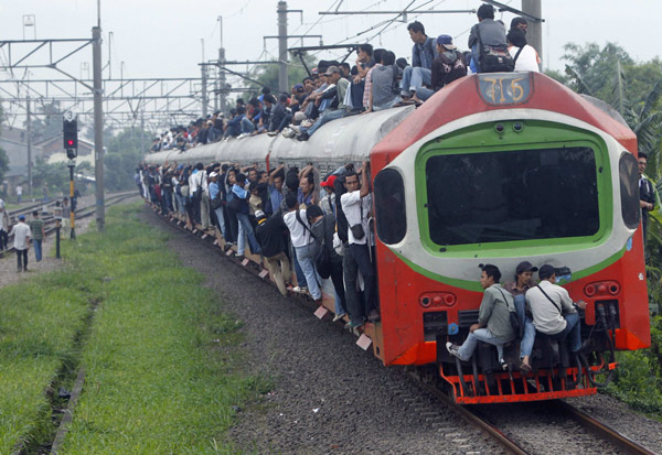 People seen outside a commuter train illegally ride the train which will transport them to Jakarta, in Depok, Indonesia&apos;s West Java province May 31, 2010. According to PT Kereta Api Indonesia, their trains operate 300 cars each day to serve about 500,000 commuters in Jakarta. In 2007 as many as 26 people were killed due to electricity shock and from falling off the roofs of trains. [Xinhua/Reuters]