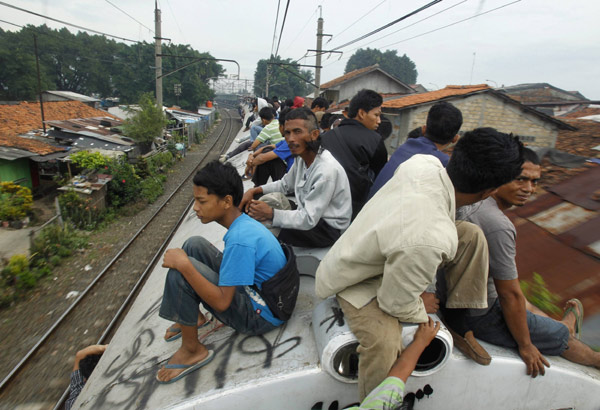 Workers sit on the roof of a commuter train as they illegally ride the train which will transport them to Jakarta, in Depok, Indonesia&apos;s West Java province May 31, 2010. According to PT Kereta Api Indonesia, their trains operate 300 cars each day to serve about 500,000 commuters in Jakarta. In 2007 as many as 26 people were killed due to electricity shock and from falling off the roofs of trains. [Xinhua/Reuters] 