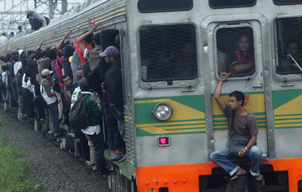 People seen outside a commuter train illegally ride the train which will transport them to Jakarta, in Depok, Indonesia&apos;s West Java province May 31, 2010. According to PT Kereta Api Indonesia, their trains operate 300 cars each day to serve about 500,000 commuters in Jakarta. In 2007 as many as 26 people were killed due to electricity shock and from falling off the roofs of trains. [Xinhua/Reuters]