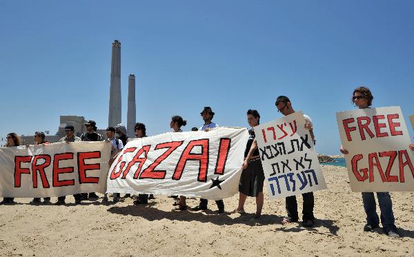 Israeli and international activists hold signs and banners on the beach during a protest against Israel&apos;s interception of Gaza-bound ships near the entrance to the port of Ashdod May 31, 2010. [Xinhua]