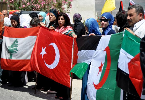 Palestinians hold flags during a protest against Isreali navy&apos;s attack in west bank city Nablus, May 31, 2010. Up to 19 civilians were killed on Monday in the deadly showdown between Israeli navy and pro- Palestinian activists onboard the Gaza-bound aid flotilla. [Xinhua]