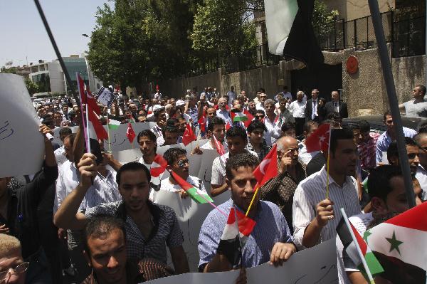 Syrian and Palestinian protesters hold up flags out of the offices of the United Nations in Damascus, capital of Syria, to denounce the Israeli raid on six aid ships in international waters, May 31, 2010. 