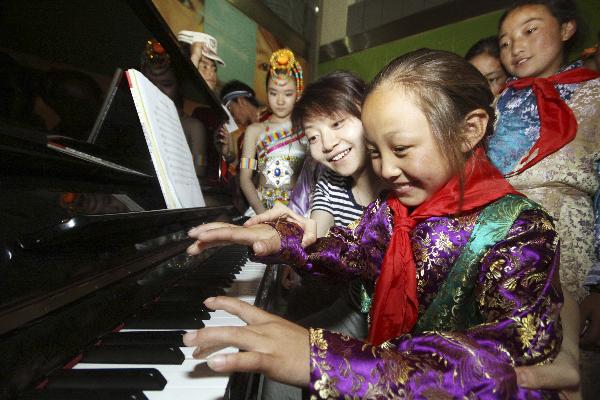 A girl from northwest China's quake-hit Yushu Prefecture plays piano at the youth activity center of Tianjin, north China, May 30, 2010.