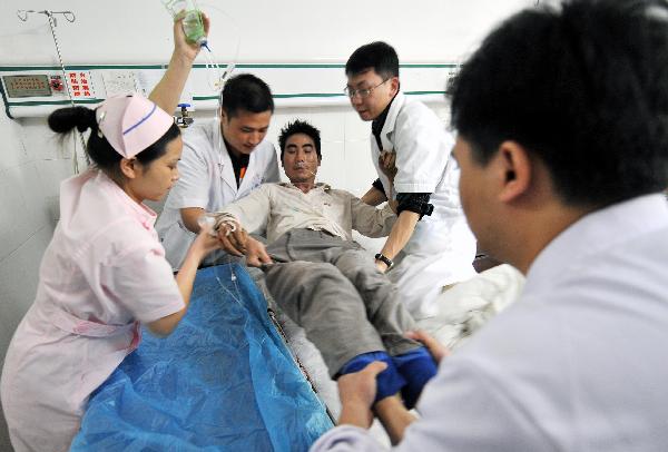 Zeng Taisheng (C) is helped by the doctors and nurses in the People's Hospital of Rucheng County, central China's Hunan Province, May 31, 2010. 