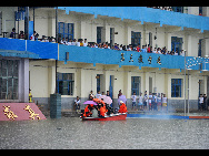 Firefighters help evacuate students from a school in Laibin, Guangxi Zhuang autonomous region, where some 600 students were stranded by the heavy rain. [Xinhua]