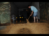 A resident clears the mud rushing into his home. [Xinhua]