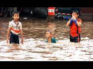 Children are play in flood in Laichenggang City, south China's Guangxi Zhuang Autonomous Region, June 1, 2010, due to the continuing severe rain and storm. [Xinhua]