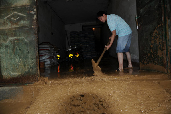 A resident clears the mud rushing into his home. [Xinhua] 