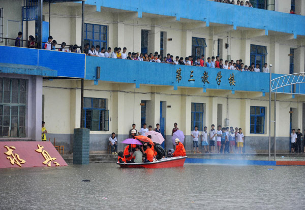 Firefighters help evacuate students from a school in Laibin, Guangxi Zhuang autonomous region, where some 600 students were stranded by the heavy rain. [Xinhua] 