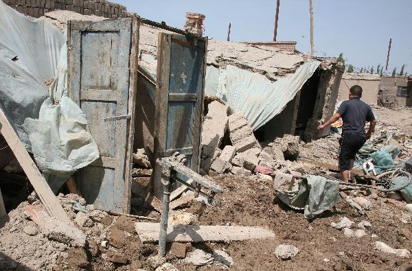 A farmer views the house damaged by snowmelt flood in Hami City, northwest China's Xinjiang Uygur Autonomous Region, June 1, 2010. With the rapid rise of temperature, snowmelt flood hit some parts of Hami recently.