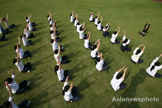 High school students sit in rows and do yoga together on a lawn at Ningbo Economy and Trade School, six days ahead of the Chinese national college entrance examination, or Gaokao, in Zhejiang province, June 1, 2010. [Photo/Asianewsphoto] 