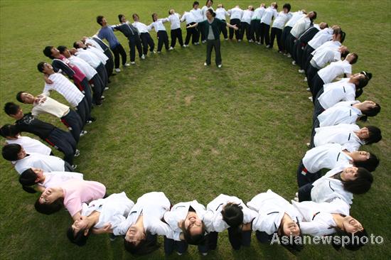 High school students stand in a circle and stretch to relieve pressure at Ningbo Economy and Trade School, six days ahead of the Chinese national college entrance examination, or Gaokao, in Zhejiang province, June 1, 2010. [Photo/Asianewsphoto]