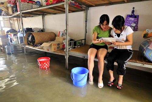 Graduating high school students prepare for the coming college entrance exam in their flooded dormitory at the No 2 High School in Du&apos;an county in South China&apos;s Guangxi Zhuang autonomous region, June 2, 2010. [Xinhua]