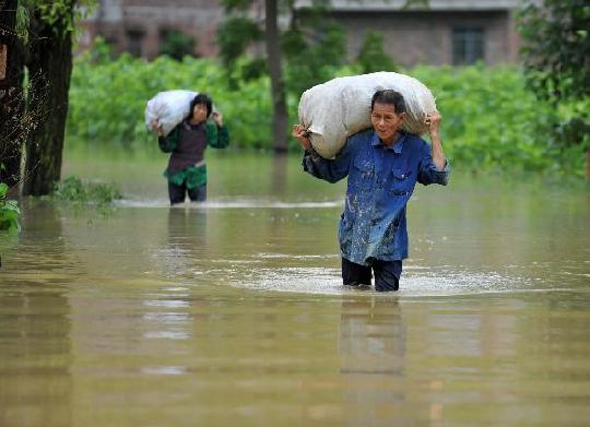 Villagers carry their belongings in the flood at Shanglang Village of Gupeng Township in Xincheng County in south China's Guangxi Zhuang Autonomous Region, June 2, 2010. [Xinhua] 
