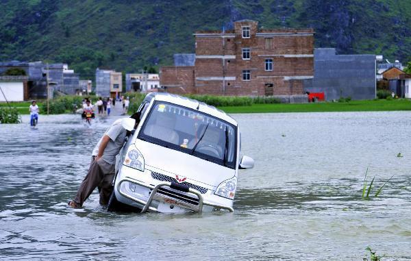 A man pushes a vehicle in flood in Yao Ethnic Autonomous County of Du'an in south China's Guangxi Zhuang Autonomous Region, June 2, 2010. The rainstorms had damaged 3,260 homes and 103,450 hectares of crops, according to Guangxi's Civil Affairs Department. [Xinhua]