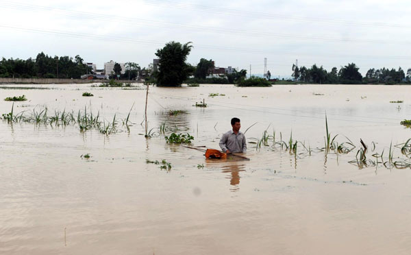 A farmer wades through his flooded farmland in Qiaogong township, Laibin city, South China's Guangxi Zhuang autonomous region, June 2, 2010. [Photo/Xinhua]