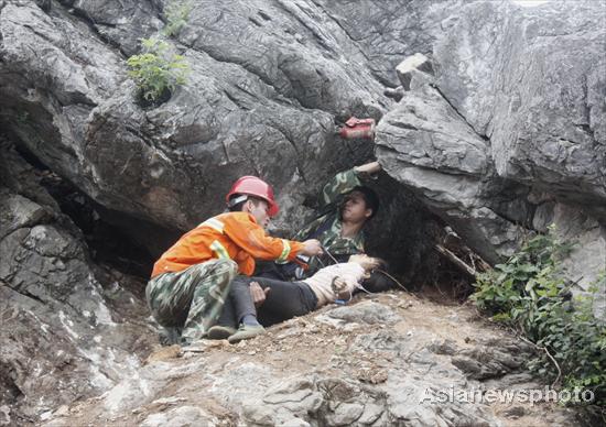 A woman is stuck between two big rocks after the collapse of a quarry in Jiujiang, South China's Jiangxi province, June 1, 2010. The 30-year-old was pulled out after two hours but died despite best efforts. The dying woman kept crying out for her baby, which greatly touched everyone present. [Photo/Asianewsphoto]