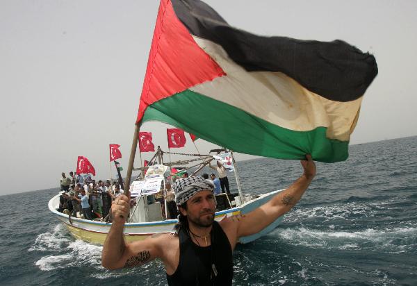 An International peace activist holds a flag during a protest against the Israeli attack on Gaza Freedom Flotilla on the sea near Gaza, June 3, 2010. [Xinhua]