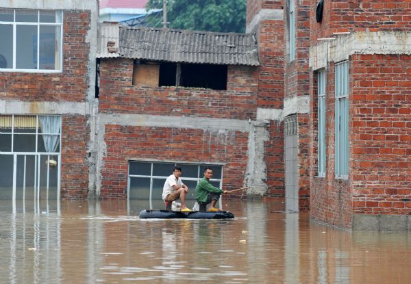 Local residents leave a damaged building by self-made raft in Laibin, south China's Guangxi Zhuang Autonomous Region, June 3, 2010. The flood triggered by heavy rain since Wednesday in Guangxi killed 38 people as of Thursday, according to local authorities. Across Guangxi, the rainstorms had battered 27 counties and nearly 80,000 people had been evacuated as of Wednesday night, the local government said.[Xinhua]