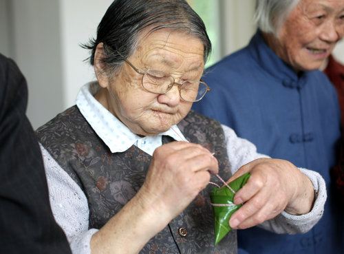 An octogenarian concentrates on wrapping a zongzi during the competition, in Nantong, East China's Jiangsu province, June 2, 2010.[