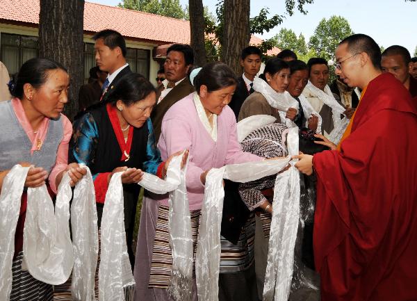 The 11th Panchen Lama(1st R) greets people upon his arrival in Lhasa, capital of southwest China&apos;s Tibet Autonomous Region, June 4, 2010. The 11th Panchen Lama arrived at Lhasa for Buddhist activities as an annual routine in recent years. [Chogo/Xinhua]