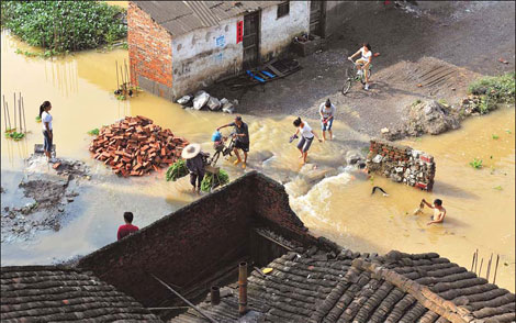 Villagers cross a flooded road in Xingbin town of Laibin city, Guangxi Zhuang autonomous region, on Friday. About 388 families, or 1,700 villagers, have been trapped in floods for four days. 