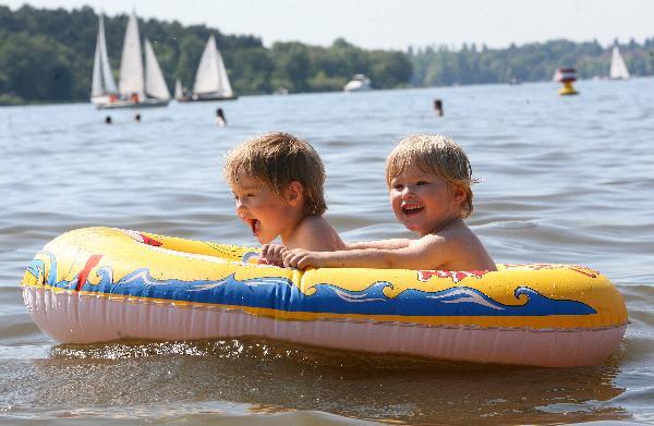 Two children sit in a rubber boat floating in a lake nearby Berlin, Germany, June 6, 2010. With sunny sky and rising temperture in most parts of Germany, people went outdoors to enjoy sunlight. [Xinhua]