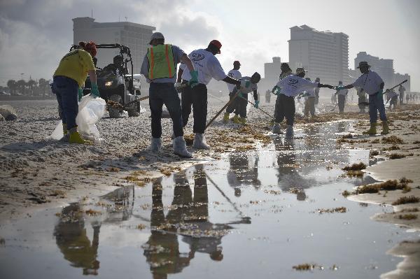 Workers clean the oil washed ashore from the BP Deepwater Horizon spill at the beach of Gulf Shores, southern Alabama, the United States, June 6, 2010. [Xinhua] 