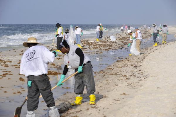 Workers clean the oil washed ashore from the BP Deepwater Horizon spill at the beach of Gulf Shores, southern Alabama, the United States, June 6, 2010. [Xinhua]