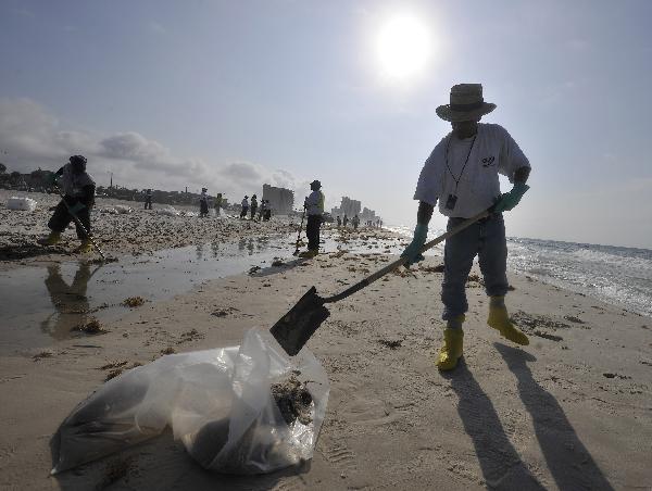 Workers clean the oil washed ashore from the BP Deepwater Horizon spill at the beach of Gulf Shores, southern Alabama, the United States, June 6, 2010. [Xinhua]