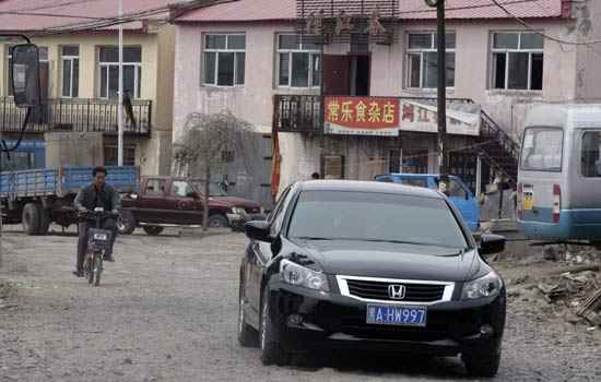 Luxury cars are now common on the dirt roads of Hongxing village, Heilongjiang province, where farmers have been compensated handsomely for their land. [China Daily]