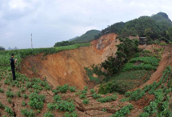 A man looks at a pit caused by land subsidence in Laibin City, southwest China's Guangxi Zhuang Autonomous Region, June 7, 2010. (Xinhua 