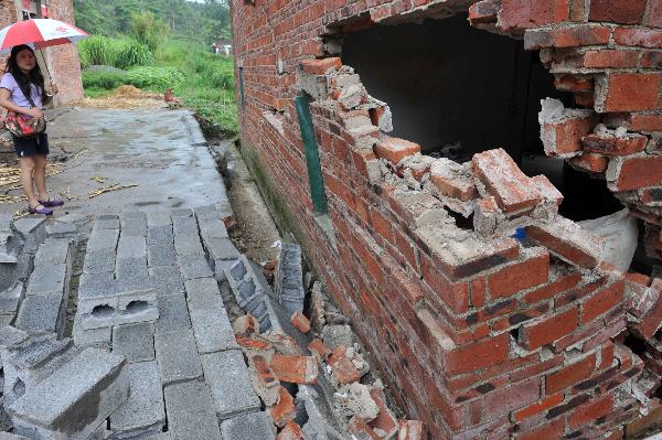 A girl watches a damaged farmhouse in Jili Village Laibin City, southwest China&apos;s Guangxi Zhuang Autonomous Region, June 7, 2010. [Xinhua]