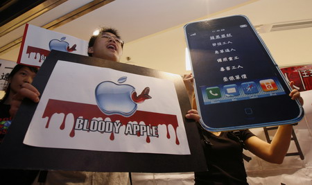 Protesters carry placards outside an Apple premier reseller store during a demonstration in Hong Kong on Tuesday as the annual general meeting of IT giant Foxconn was held. Labor activists also held protests in Taiwan after a recent spate of suicides at the company’s factories on the mainland. [BOBBY YIP / REUTERS]