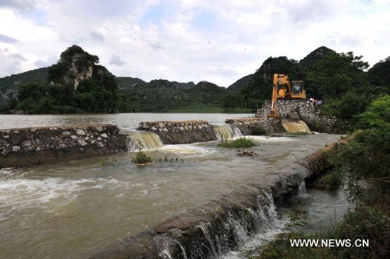 An excavator works on Lingkou Reservoir to discharge floods in Laibin City, southwest China's Guangxi Zhuang Autonomous Region, on June 8, 2010. 