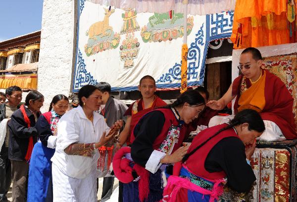 The 11th Panchen Lama gives head-touch blessings to local devotees in front of Sanyai Monastery in Nedong County of Shannan Prefecture, southwest China's Tibet Autonomous Region, on June 8, 2010. The 11th Panchen Lama finised Tuesday the two-day visit in south Tibet's Shannan Prefecture where he held large prayer services and gave head-touch blessings to more than 5,000 local devotees. (Xinhua/Chogo