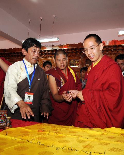 The 11th Panchen Lama (R) writes an inscription for Tibet College of Tibetan Medicine in Lhasa, capital of southwest China's Tibet Autonomous Region, June 9, 2010. The 11th Panchen Lama visited Tibet University and Tibet College of Tibetan Medicine in Lhasa on Wednesday. (Xinhua/