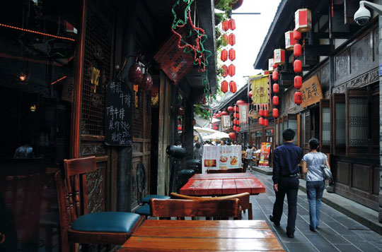 By the riverside or at foothills, clusters of people sit around a table shielded by a sun umbrella playing mah-jongg.