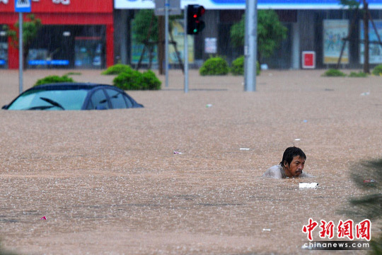 A man is seen trapped in a waterlogging street in Wuzhou, Guangxi Zhuang Autonomous Region of south China. Heavy rainstorm hit Wuzhou on June 9, 2010, causing severe waterlogging in the area. [Chinanews.com.cn]