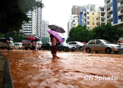 People walk in a waterlogging street in Wuzhou, Guangxi Zhuang Autonomous Region of south China. Heavy rainstorm hit Wuzhou on on June 9, 2010, causing severe waterlogging in the area. [gxnews.com.cn]