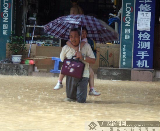 People walk in a waterlogging street in Wuzhou, Guangxi Zhuang Autonomous Region of south China. Heavy rainstorm hit Wuzhou on June 9, 2010, causing severe waterlogging in the area. [Chinanews.com.cn]