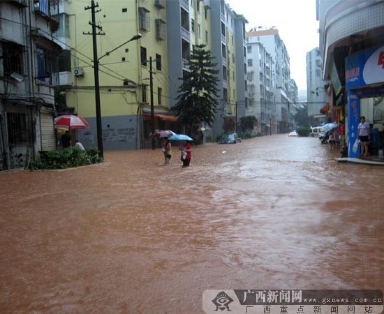 People walk in a waterlogging street in Wuzhou, Guangxi Zhuang Autonomous Region of south China. Heavy rainstorm hit Wuzhou on on June 9, 2010, causing severe waterlogging in the area. [gxnews.com.cn]