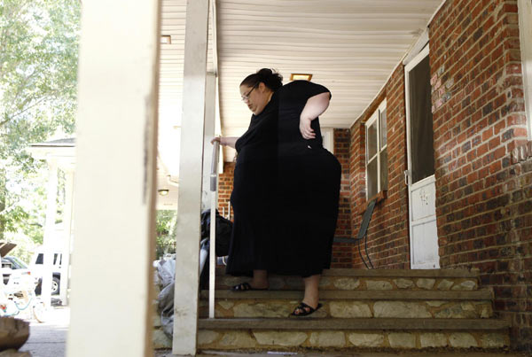 Donna Simpson walks down her front steps to watch her daughter play in the yard at her home in Old Bridge, New Jersey June 8, 2010. Simpson, 42, who weighs more than 600 pounds (272 kg) and aims to reach 1,000 pounds (455 kg), is waging a campaign to become the world&apos;s heaviest living woman, admitting that she is as hungry for attention as she is for calorie-rich food. [China Daily/Agencies]